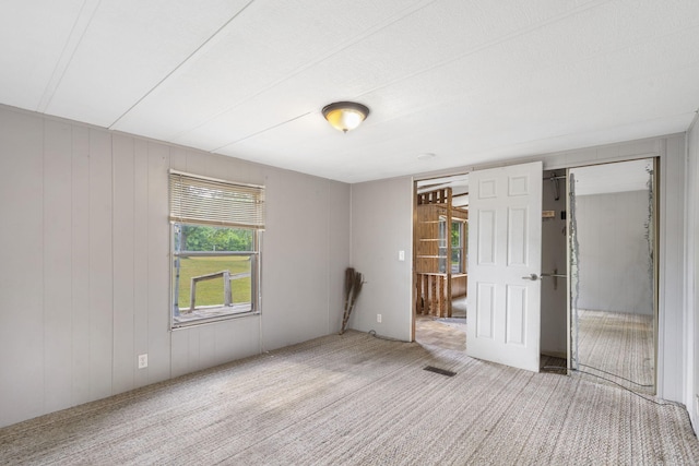 empty room with carpet floors and wooden walls