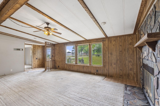 unfurnished living room featuring a textured ceiling, lofted ceiling with beams, wooden walls, and ceiling fan