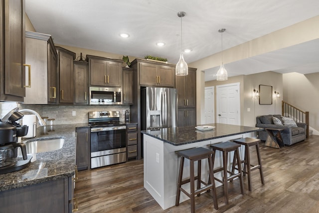 kitchen featuring stainless steel appliances, a sink, dark wood-style flooring, dark brown cabinets, and open floor plan