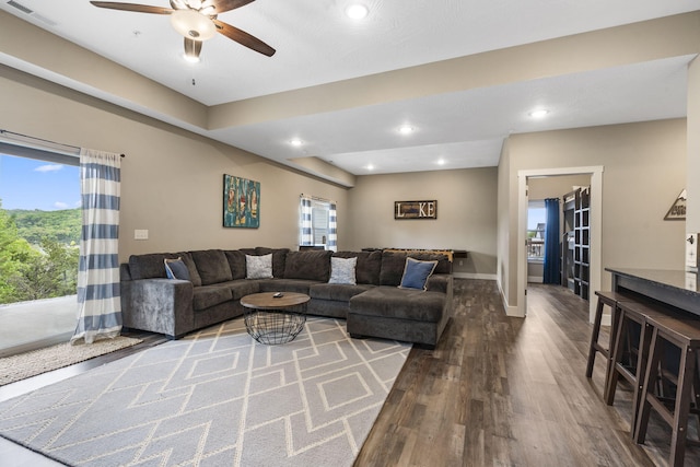living room with wood finished floors, visible vents, a ceiling fan, and a healthy amount of sunlight
