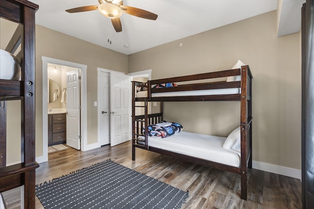 bedroom featuring baseboards, ensuite bathroom, wood finished floors, and a ceiling fan