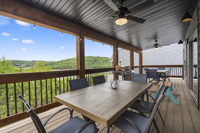 wooden deck featuring area for grilling, ceiling fan, and outdoor dining space