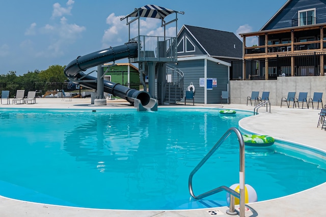 pool featuring a water slide, a patio, and fence