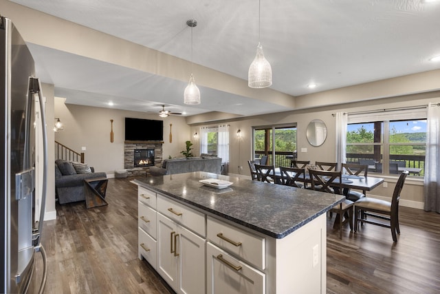 kitchen with a kitchen island, a stone fireplace, dark hardwood / wood-style floors, white cabinets, and stainless steel refrigerator