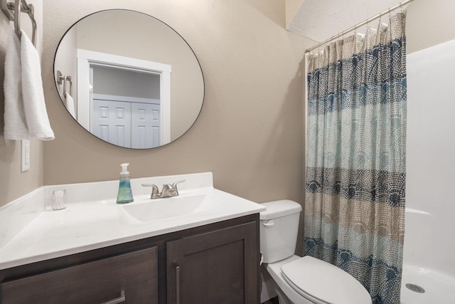 bathroom with walk in shower, vanity, and toilet