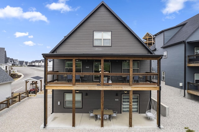 back of property featuring fence, a balcony, and a patio