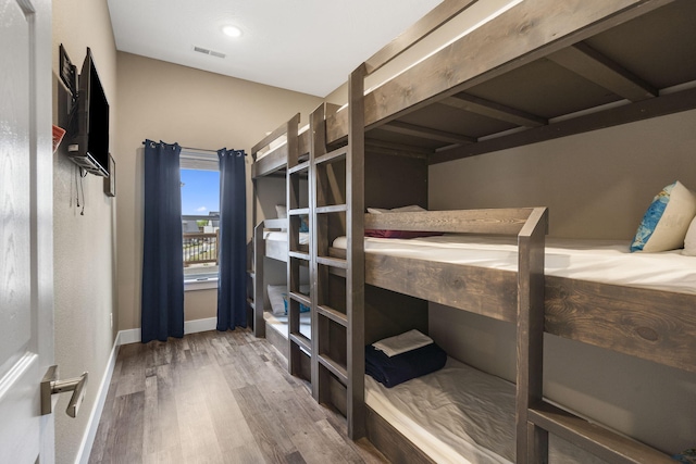 bedroom with wood finished floors, visible vents, and baseboards