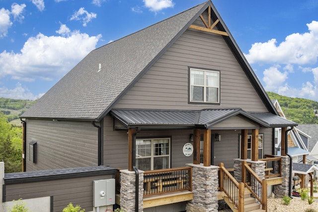 view of front of home with a porch, stone siding, and metal roof