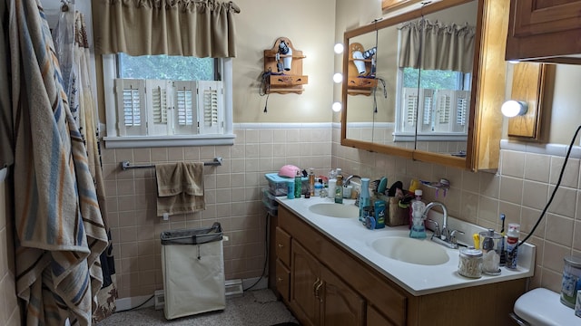 bathroom with toilet, plenty of natural light, tile walls, and vanity