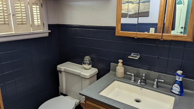 bathroom featuring vanity, tile walls, and toilet