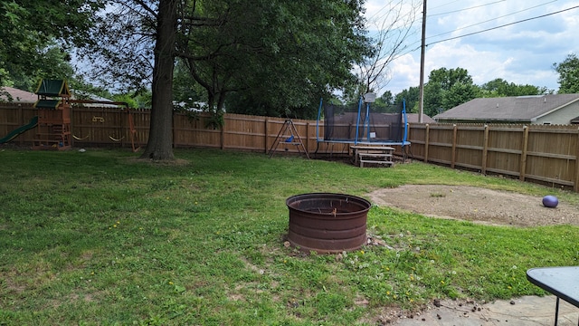 view of yard with a trampoline and an outdoor fire pit