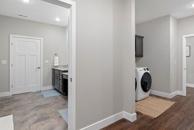 clothes washing area featuring cabinets, washer / dryer, and light wood-type flooring