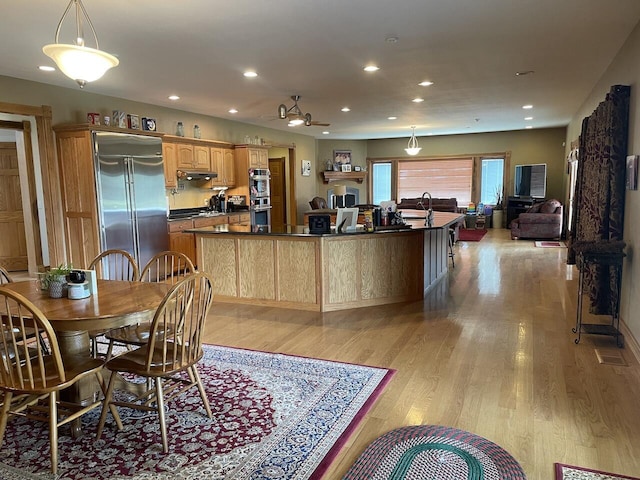 1179 County Road 1050, Willow Springs, MO 65793 - interior space featuring dark countertops, stainless steel appliances, light wood finished floors, a center island with sink, and under cabinet range hood
