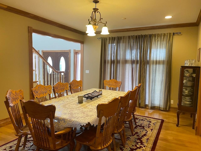 dining area with a notable chandelier, light wood-type flooring, and ornamental molding