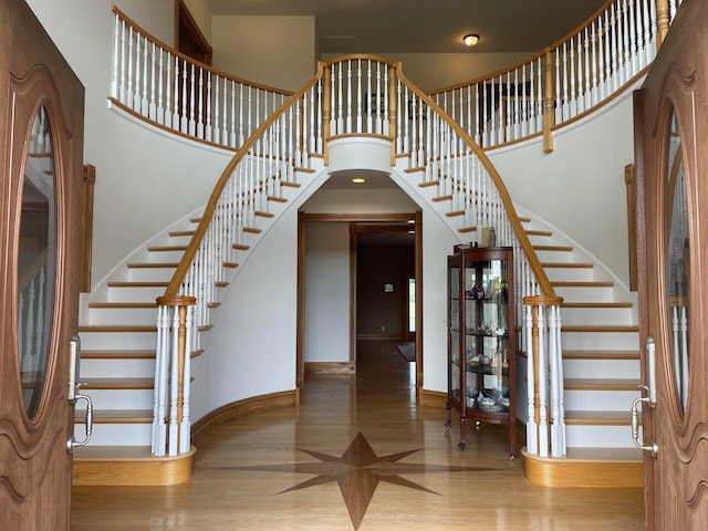 staircase with hardwood / wood-style floors and a high ceiling