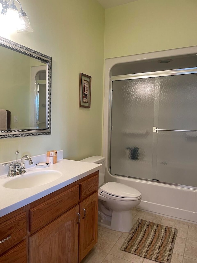 full bathroom featuring tile patterned flooring, shower / bath combination with glass door, vanity, and toilet