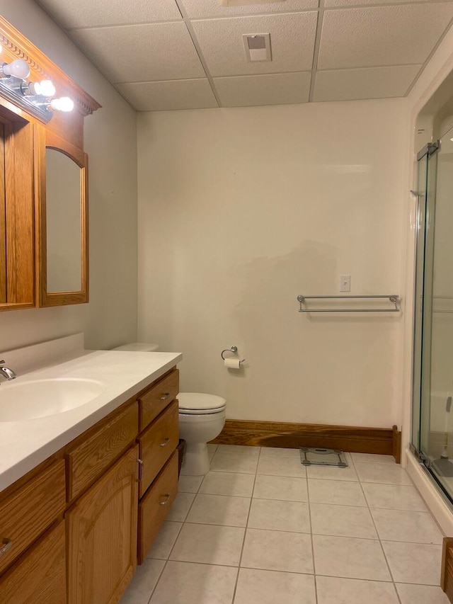 bathroom featuring vanity, toilet, a paneled ceiling, tile patterned flooring, and a shower with door