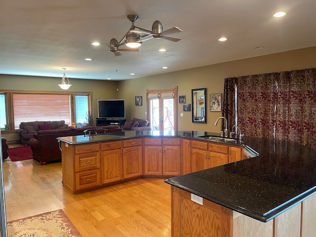 kitchen with ceiling fan, sink, light hardwood / wood-style floors, kitchen peninsula, and pendant lighting