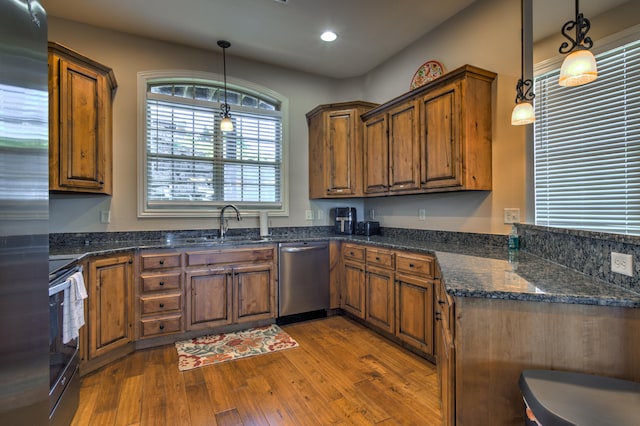 kitchen with pendant lighting, hardwood / wood-style flooring, stainless steel appliances, and sink