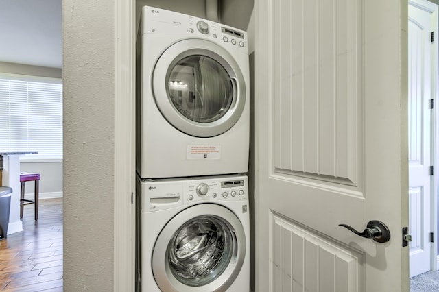 washroom with stacked washer and clothes dryer and hardwood / wood-style flooring