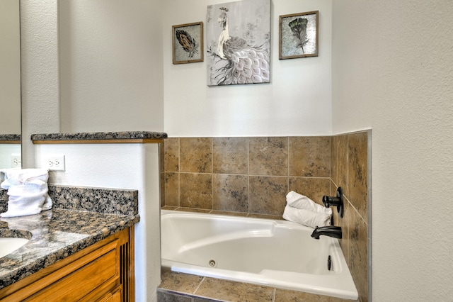 bathroom featuring a relaxing tiled tub and vanity