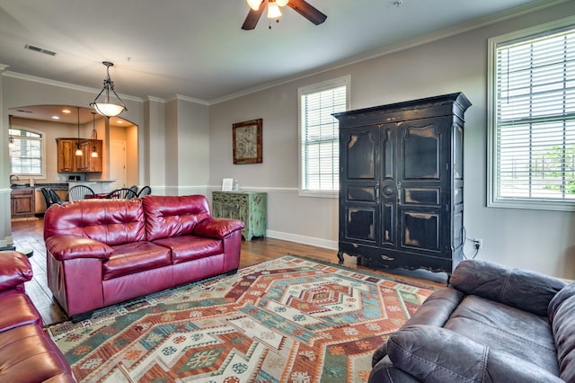 living room with ceiling fan, ornamental molding, and dark wood-type flooring