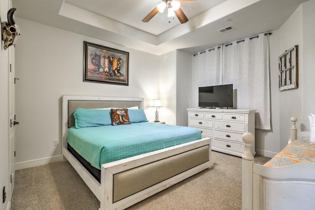 carpeted bedroom featuring a tray ceiling and ceiling fan