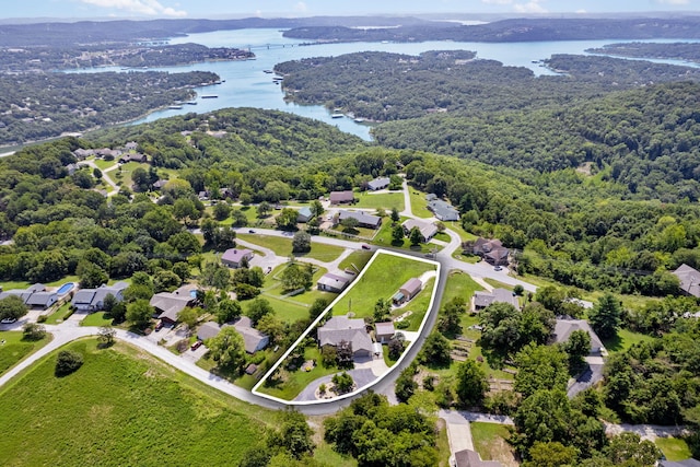 drone / aerial view featuring a view of trees, a water view, and a residential view