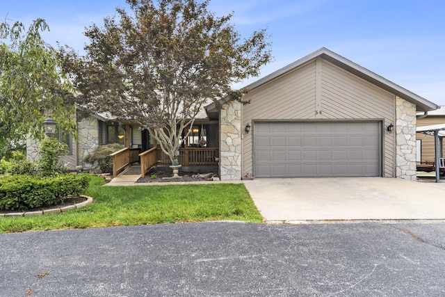 view of front of property with a front lawn, driveway, stone siding, covered porch, and an attached garage