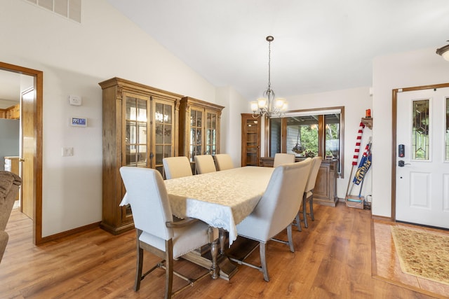 dining room featuring hardwood / wood-style floors, a notable chandelier, and lofted ceiling