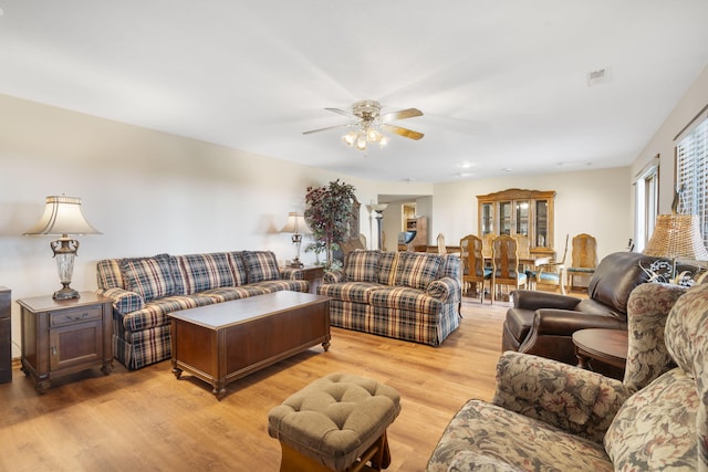 living room with a ceiling fan, visible vents, and light wood-style flooring