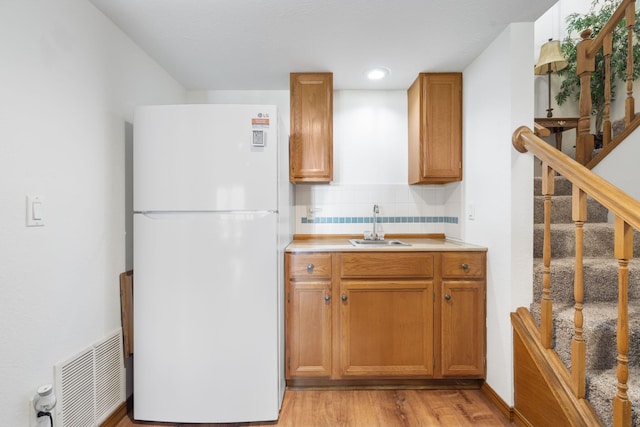 kitchen with light countertops, visible vents, a sink, freestanding refrigerator, and tasteful backsplash