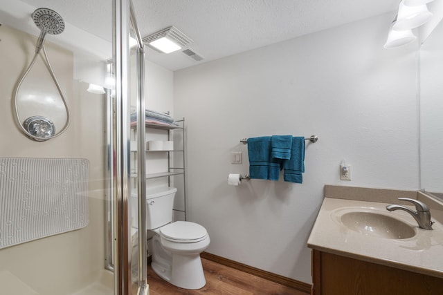 bathroom with vanity, a shower with shower door, toilet, a textured ceiling, and wood-type flooring