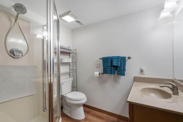 full bath with wood finished floors, a textured ceiling, a stall shower, vanity, and toilet