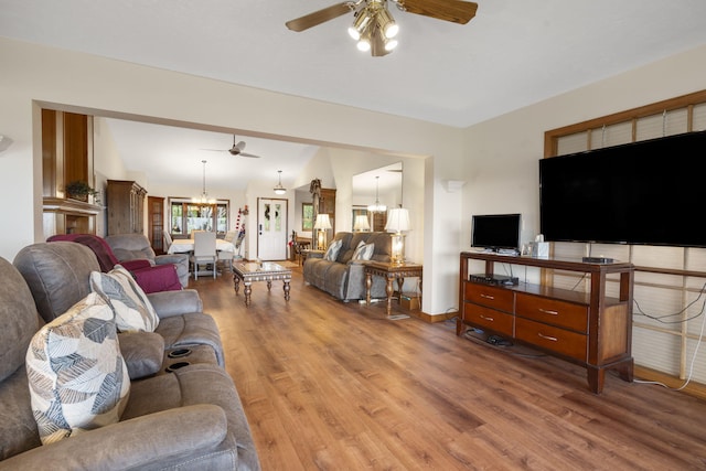 living room with ceiling fan with notable chandelier and wood-type flooring