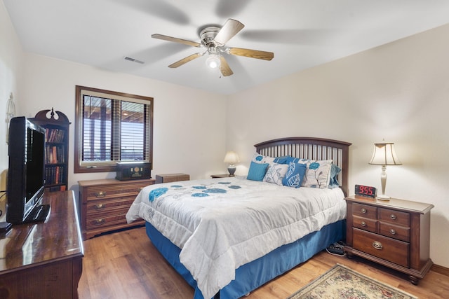 bedroom with wood finished floors, visible vents, and ceiling fan