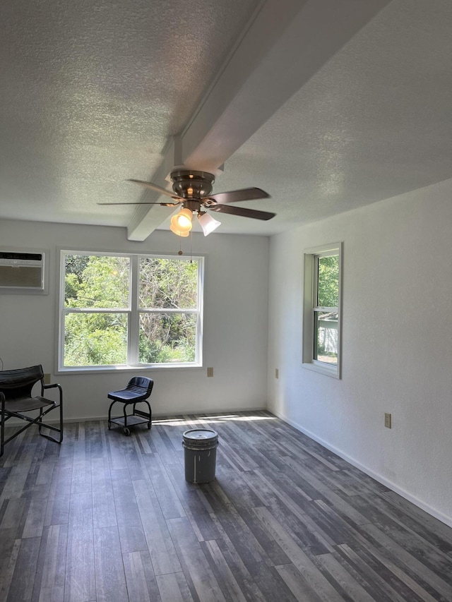 living area featuring dark wood finished floors, a wall mounted air conditioner, a textured ceiling, and a ceiling fan