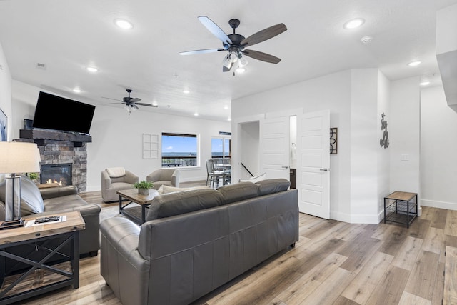 living room with a fireplace, light hardwood / wood-style flooring, and ceiling fan