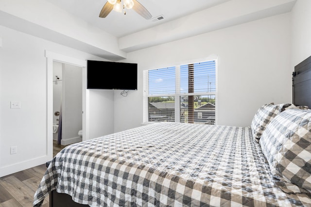 bedroom featuring ceiling fan, connected bathroom, a barn door, and hardwood / wood-style floors