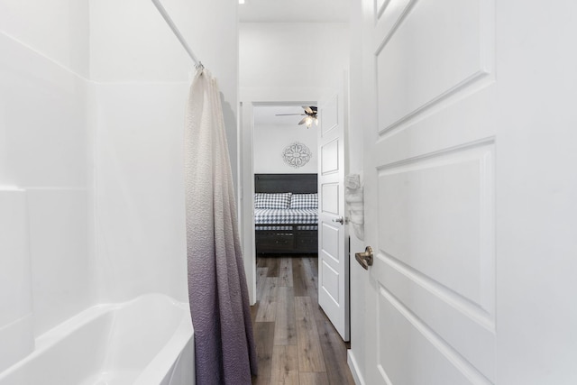 bathroom with hardwood / wood-style flooring, ceiling fan, and shower / bath combo