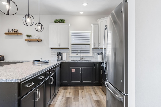 kitchen with light hardwood / wood-style flooring, sink, stainless steel appliances, backsplash, and white cabinetry