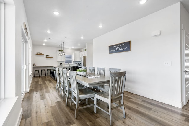 dining space with wood-type flooring and an inviting chandelier