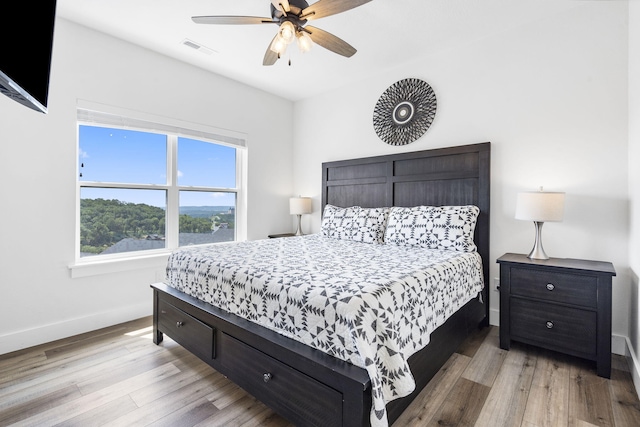 bedroom with multiple windows, ceiling fan, and light hardwood / wood-style floors