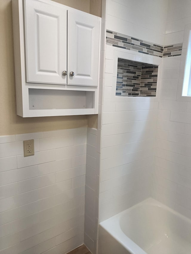 bathroom with tile walls and tiled shower / bath combo