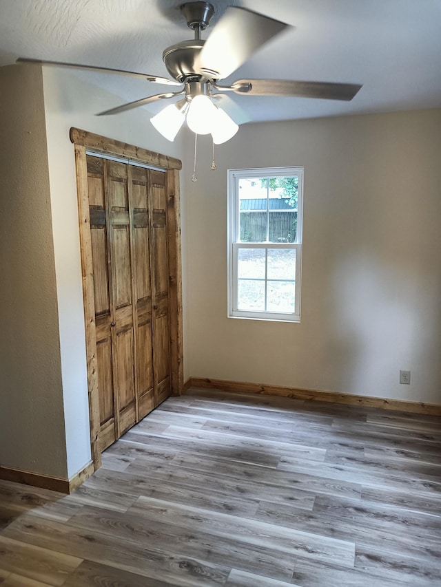 unfurnished bedroom with a closet, baseboards, a ceiling fan, and light wood-type flooring