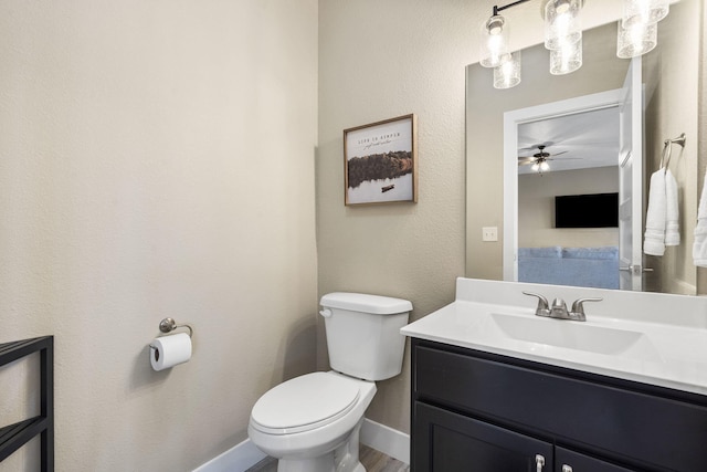 bathroom with baseboards, a ceiling fan, vanity, and toilet