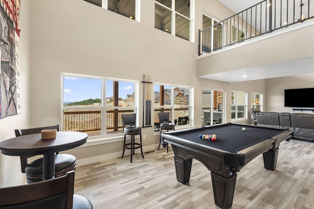 recreation room featuring a towering ceiling, light hardwood / wood-style floors, and billiards