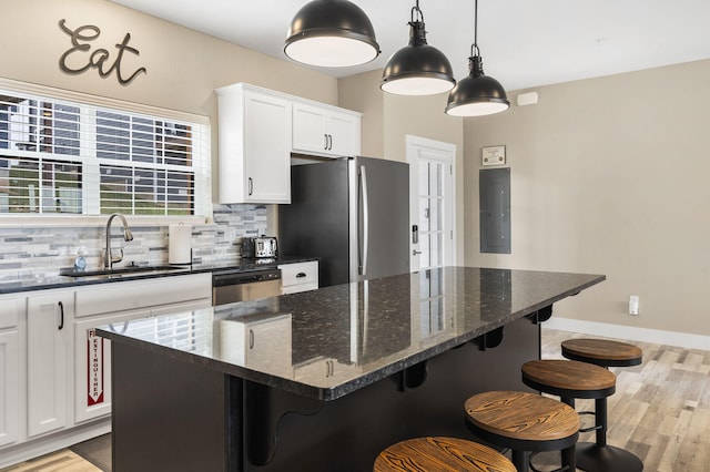 kitchen with electric panel, a center island, a sink, backsplash, and appliances with stainless steel finishes