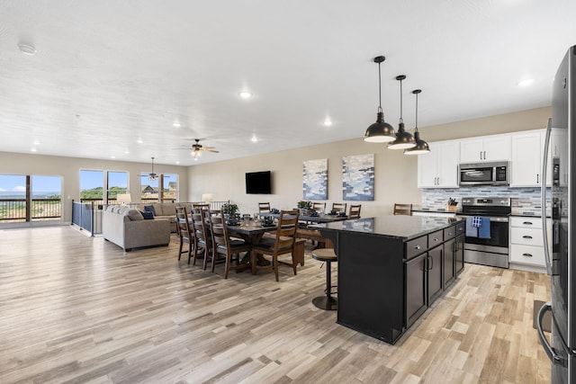 kitchen with a kitchen island, ceiling fan, light hardwood / wood-style floors, white cabinetry, and appliances with stainless steel finishes