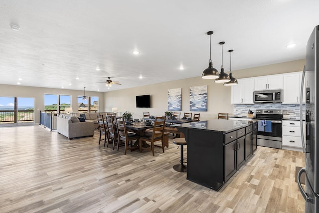 kitchen with a center island, open floor plan, a breakfast bar area, light wood finished floors, and appliances with stainless steel finishes